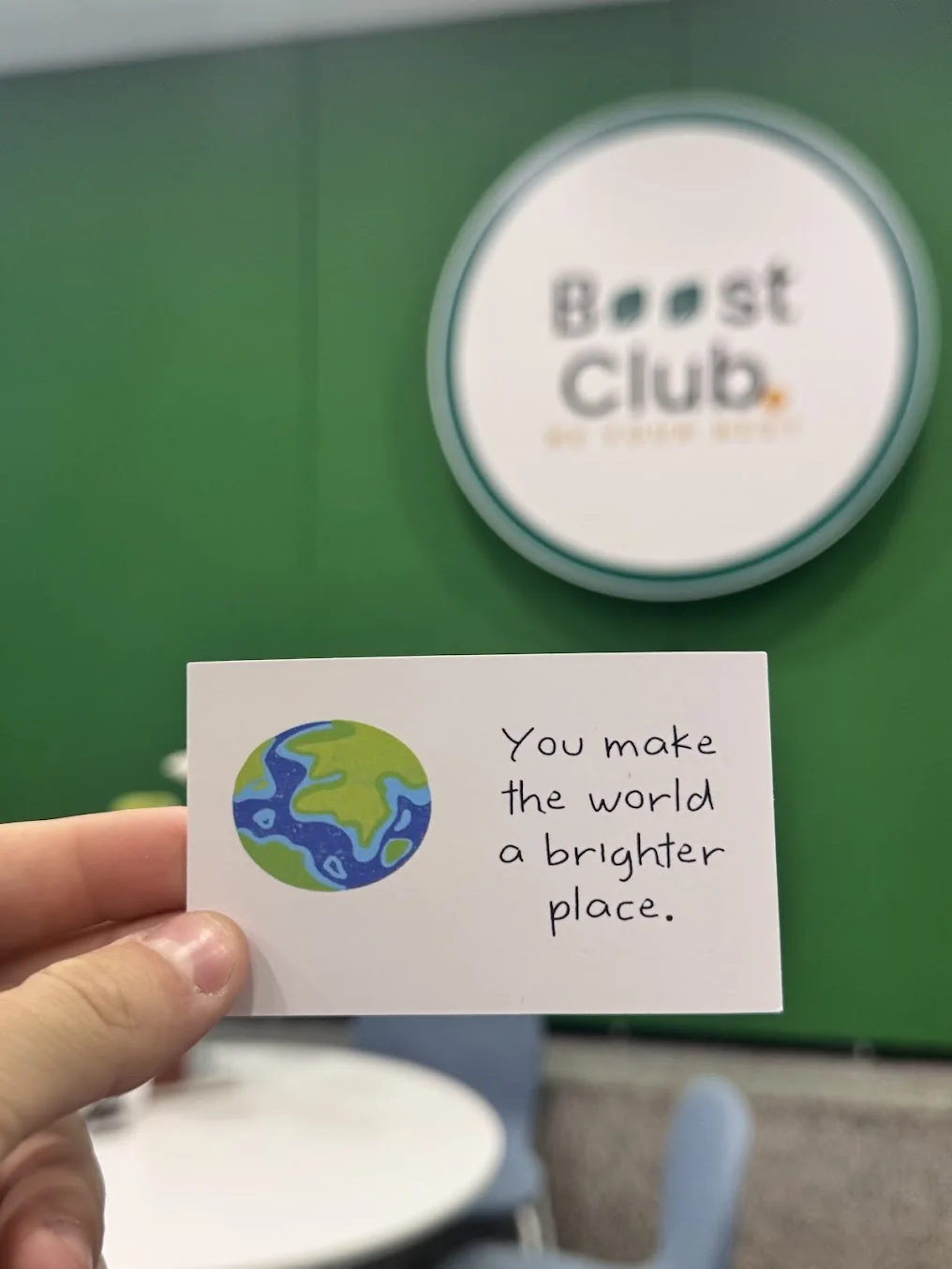 Un mesaj de bun venit în fața peretelui verde Boost Club
