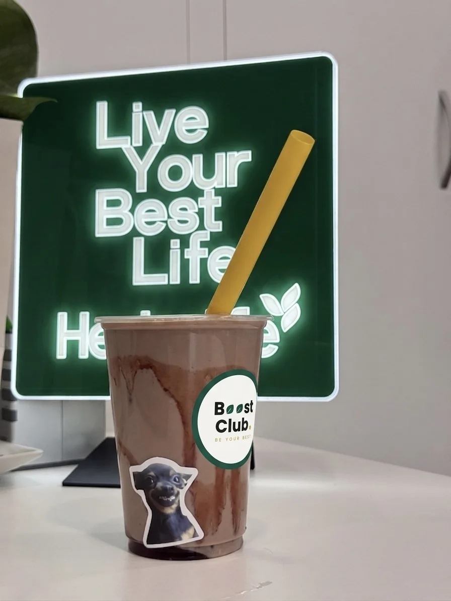 O băutură Boost Club pe masă, lângă un mesaj motivațional